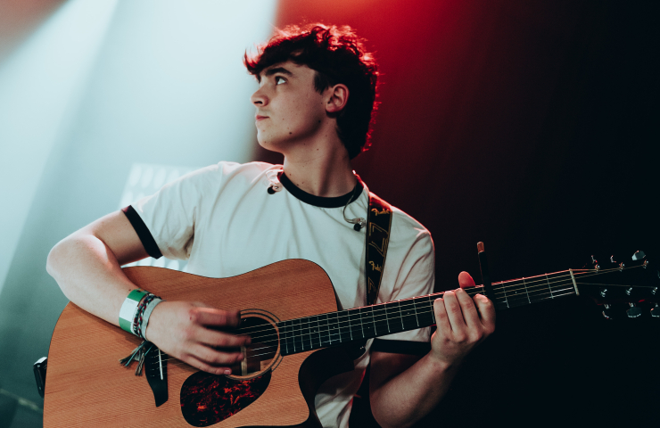 joven con guitarra encima del escenario