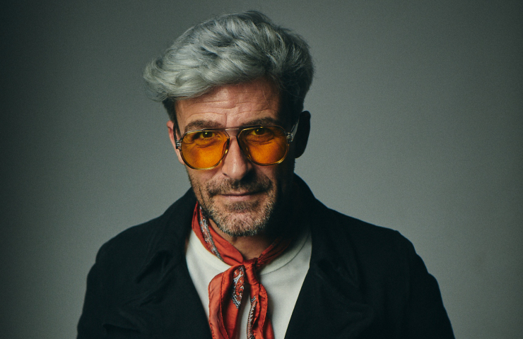 hombre con gafas con cristales amarillos, pelo corto blanco, pañuelo rojo al cuello