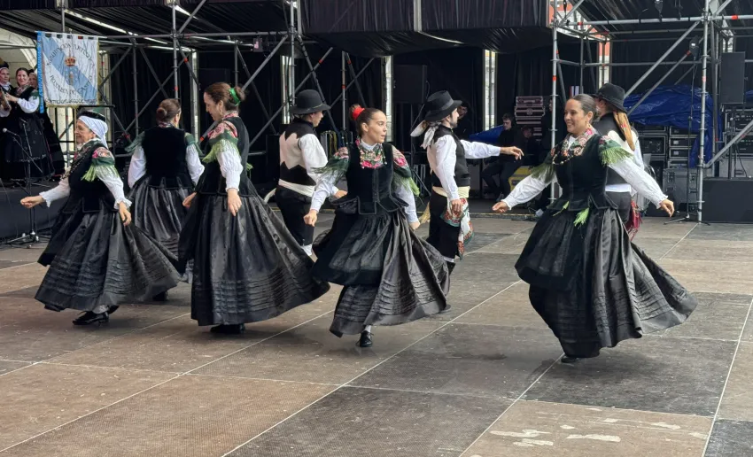 chicas vestidas con trajes regionales bailando sobre el escenario