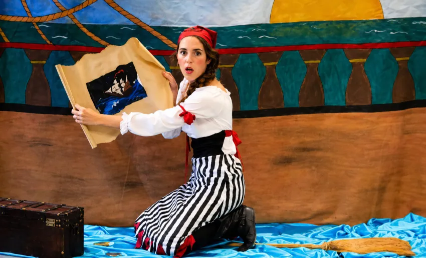mujer disfrazada de pirata, cara de asombro con un mapa en las manos