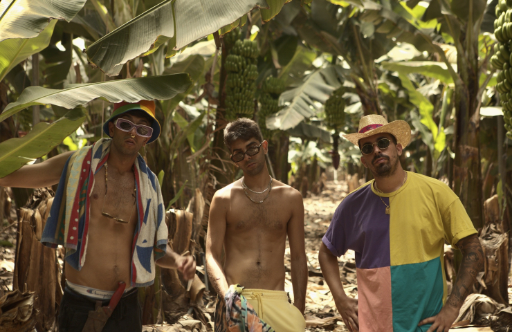 Tres chicos con atuendo veraniego en un entorno de palmeras