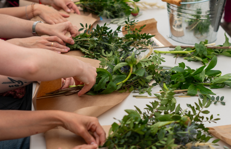 detalle de manos trabajando ramilletes de plantas sobre una mesa