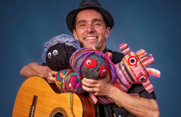 señor con guitarra y marionetas en las manos sonriente