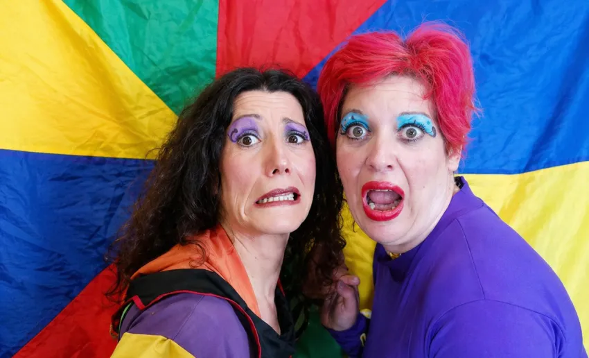 dos mujeres con los ojos muy maquillados con sombra azul, esto de miedo y sorpresa en la cara, fondo de tela de colores