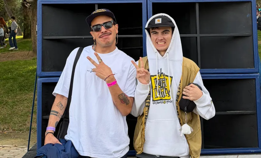 dos chicos sonriendo de frente, gorra, sudadera y camiseta blancas, sonrientes, haciendo con los dedos el símbolo de la v