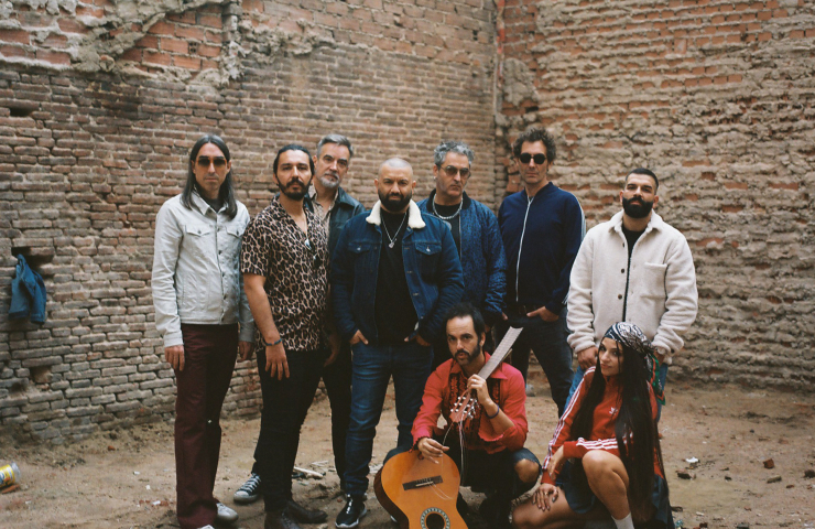 Ocho hombres frente a un edificio de ladrillo